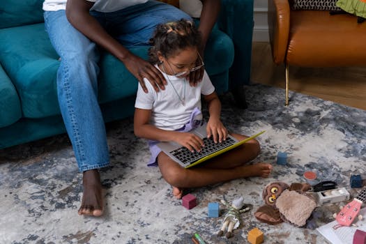 A child and father engaging in educational play with a laptop indoors.