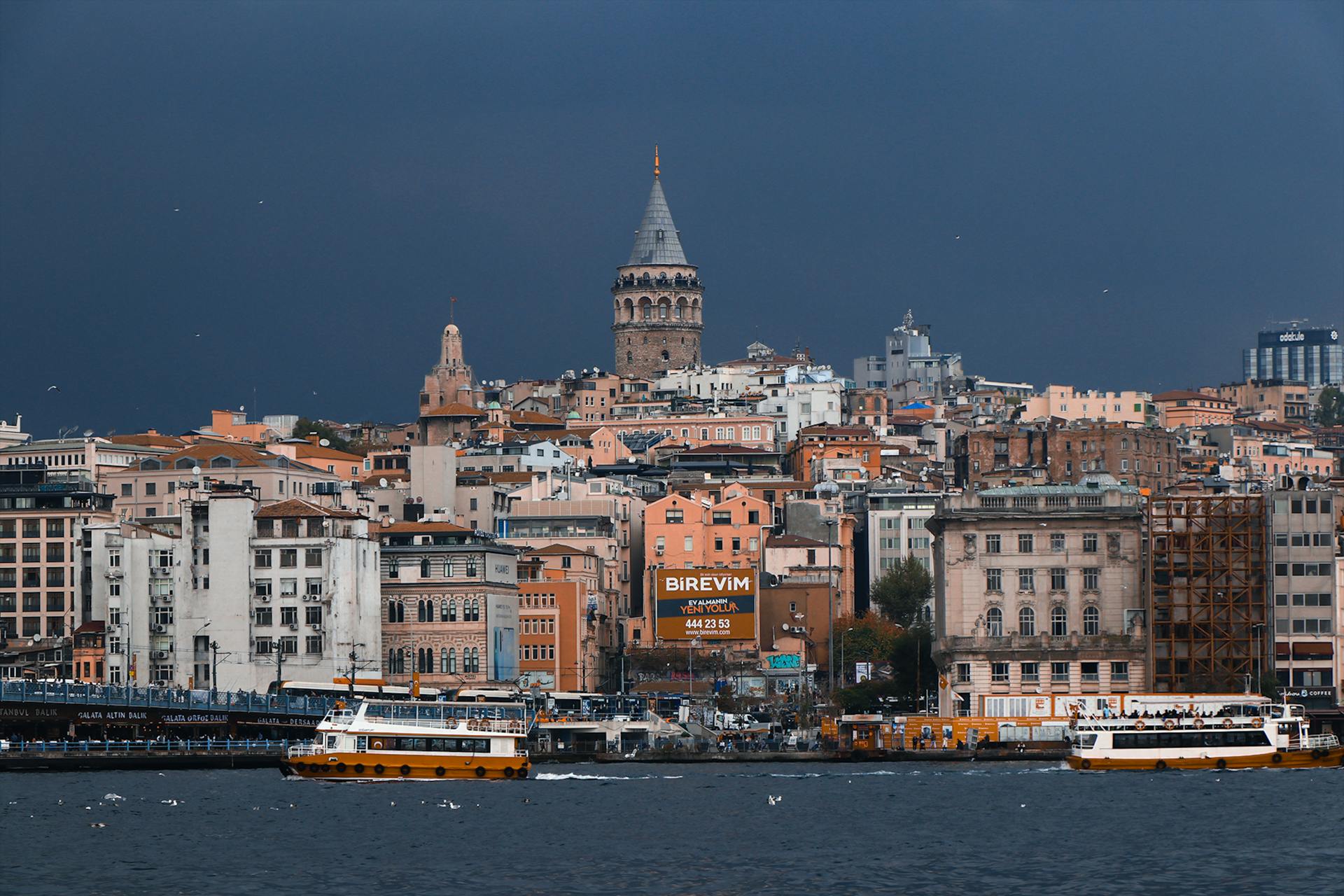 A vibrant view of Istanbul's skyline with the historic Galata Tower and ferry boats on the water.