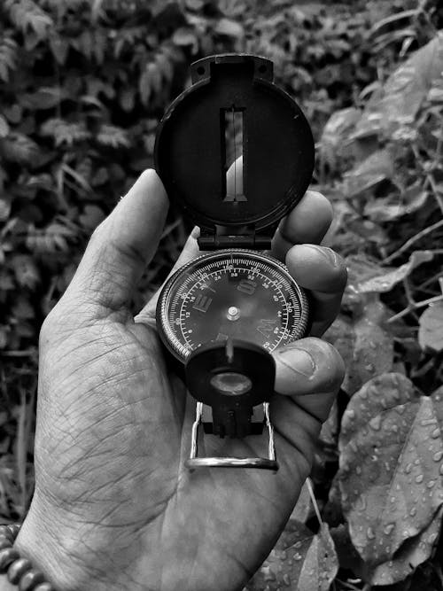 Grayscale Photo of Person Holding a Modern Compass with Sight Device