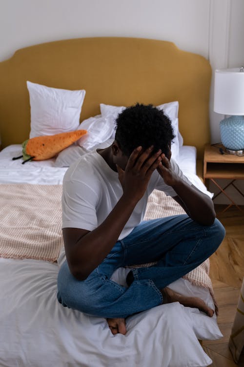 Mann Im Weißen T Shirt Und In Den Blauen Jeans, Die Auf Bett Sitzen