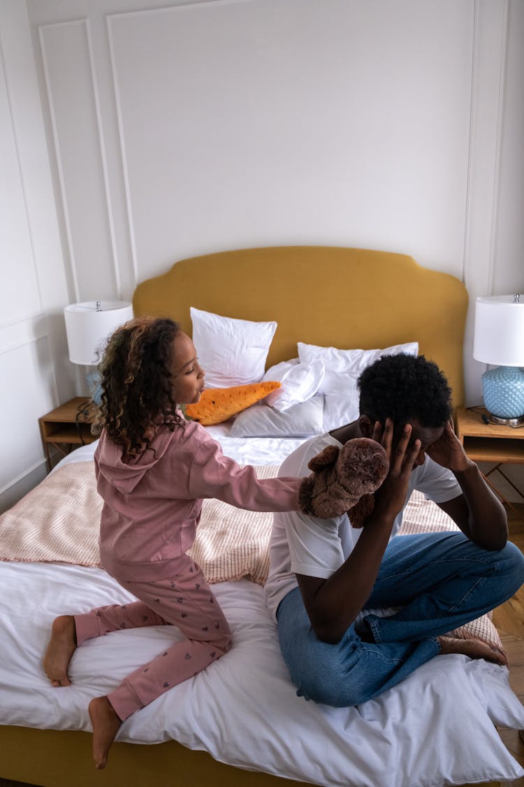 A Young Girl Talking To Her Father Sitting On The Bed