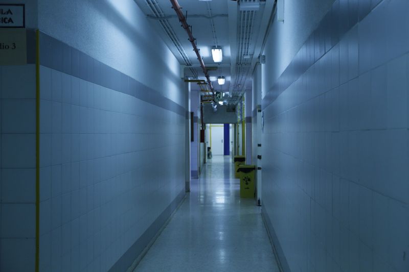 A deserted, dimly lit hallway with tiled walls and overhead lights.