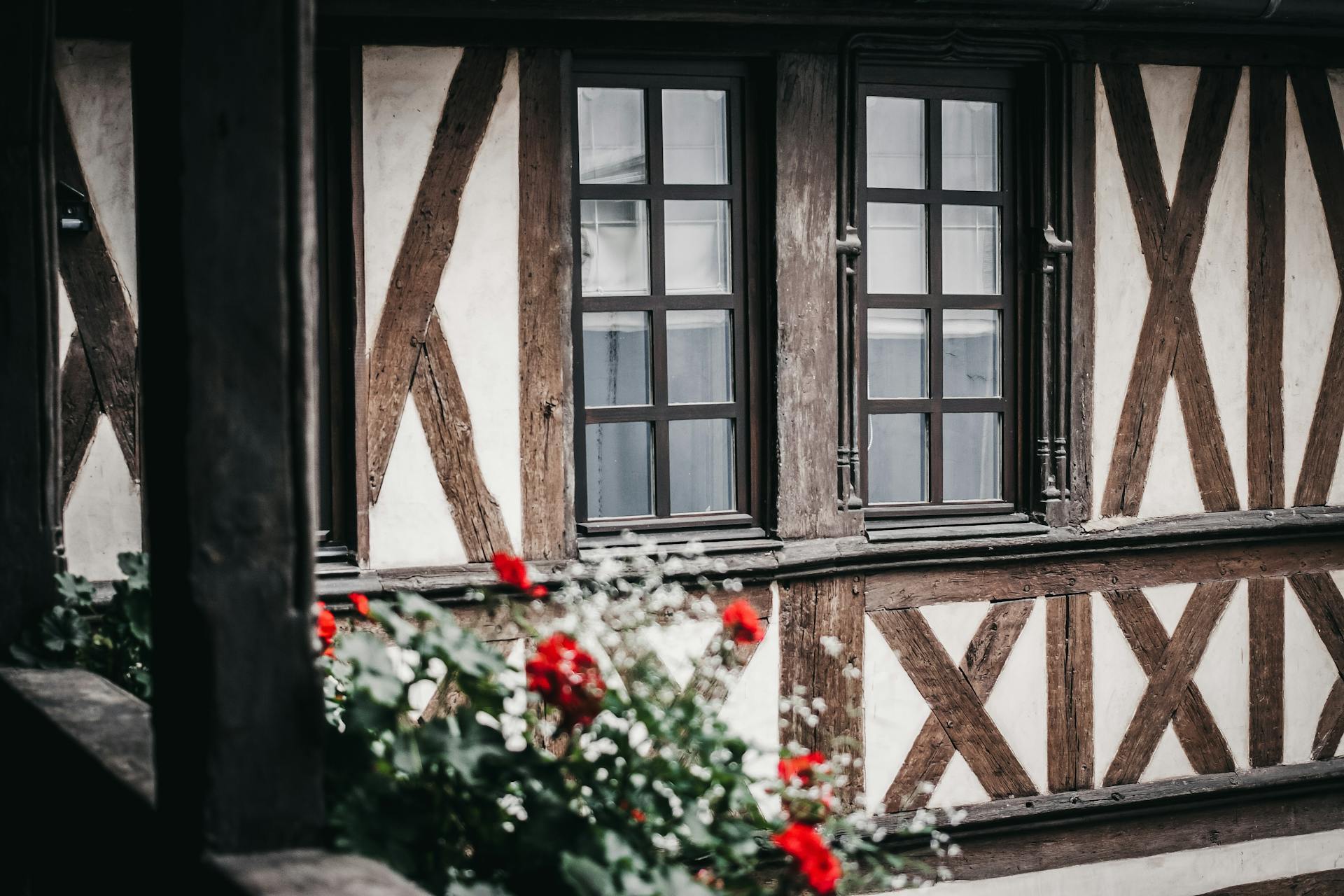 Explore the rustic elegance of a French half-timbered house adorned with vibrant flowers.