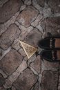 From above of crop anonymous female traveler in stylish moccasins standing on aged cobblestone street near golden triangle detail with carved owl