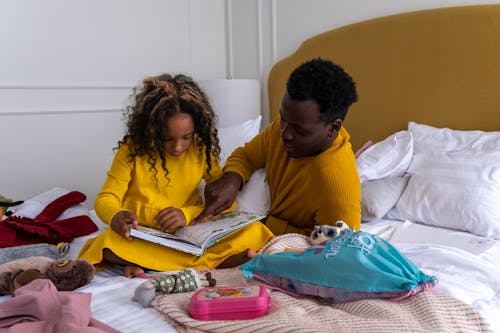 Free A Man Teaching His Daughter while Sitting on the Bed Stock Photo