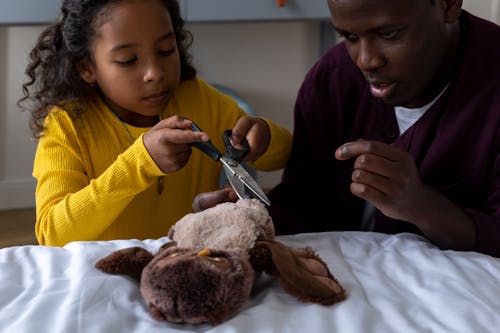 A Little Girl and her Dad Repairing a Soft Toy Together