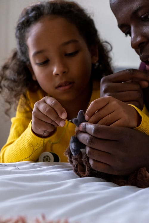 Close up of Father and Daughter Sewing a Soft Toy Together 