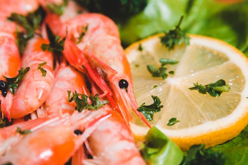 Free Closeup of whole yummy shrimps with fresh lemon circle and parsley pieces on lettuce leaf on blurred background Stock Photo