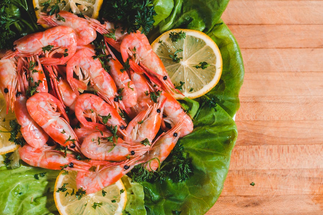 Free Overhead view of appetizing cooked shrimps with cut fresh parsley and juicy lemon slices on table Stock Photo
