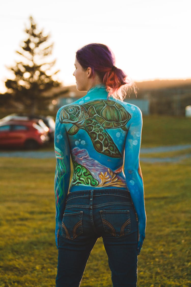 Sportswoman In Athletic Shirt With Turtle Ornament On Meadow