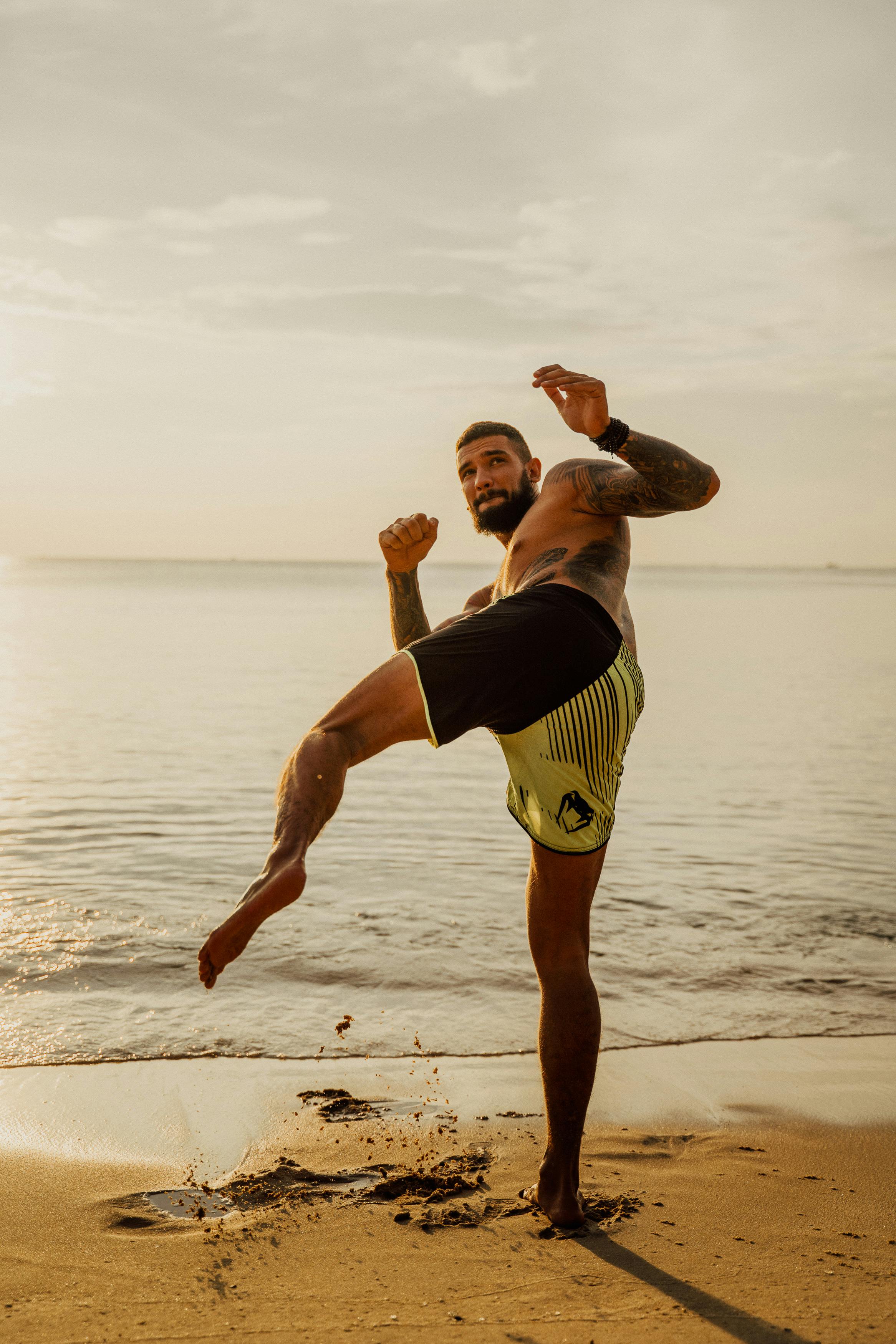 a man practicing kickboxing while on the seashore