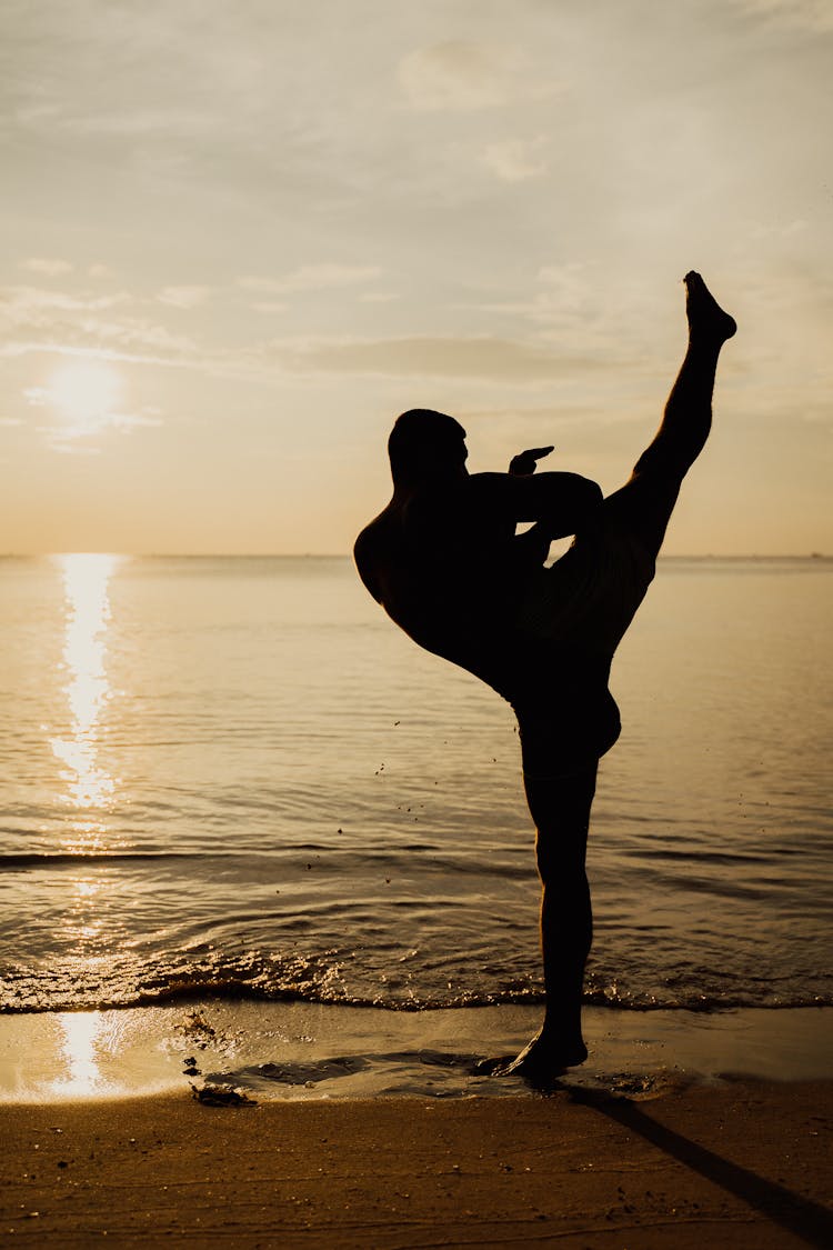 Silhouette Of Man Practicing Kickboxing On The Seashore During Sunset