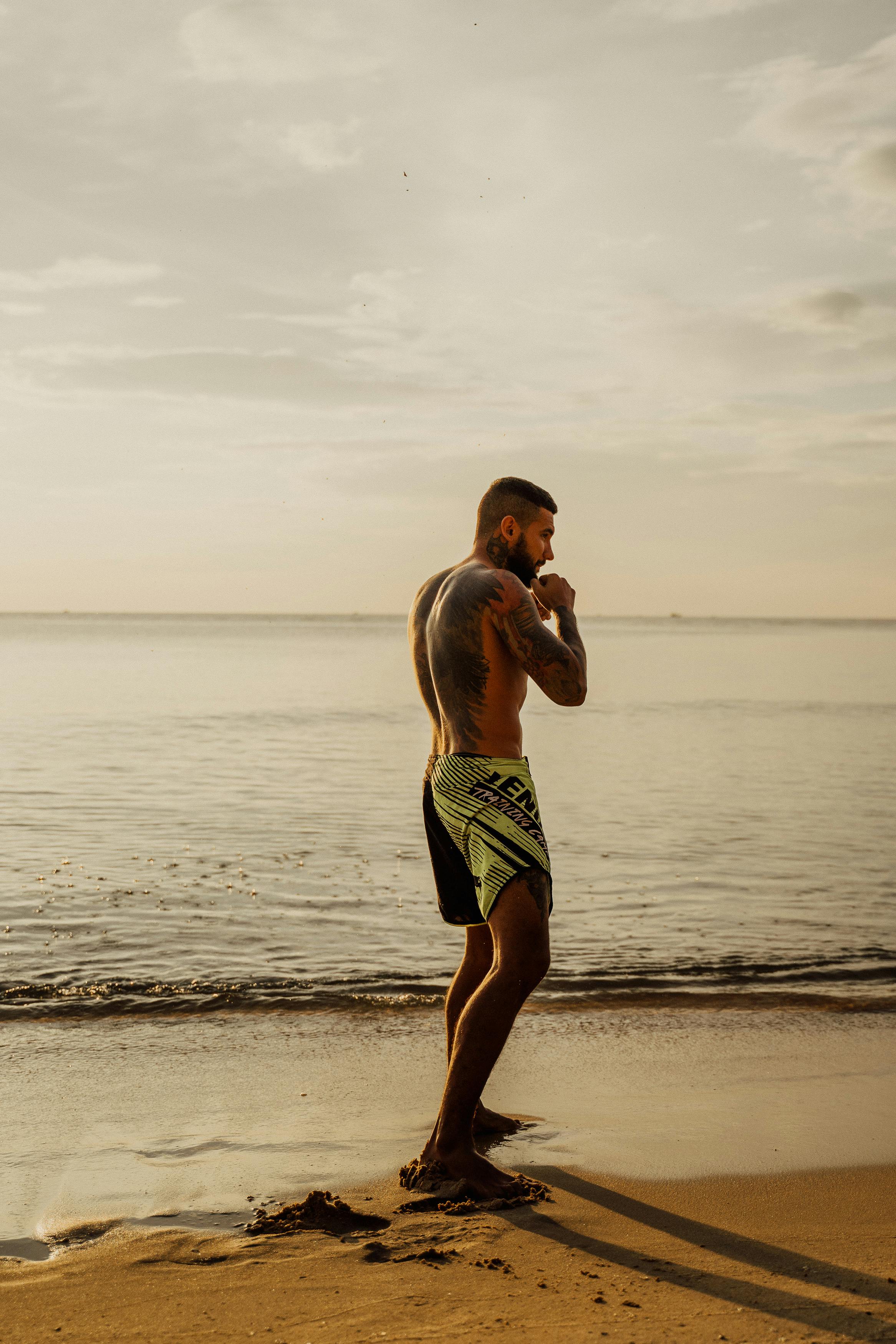 man in black shorts standing on the seashore