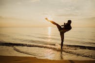 在日落期间，武术家在海滩上表演高踢，创造一个动态的场景