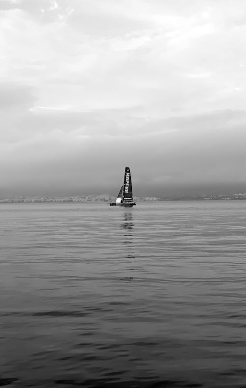 Grayscale Photo of a Sailboat in the Middle of the Sea