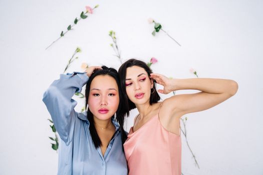 两位身着时尚服装的女性肖像，以极简的花卉为背景，散发着自信与风格