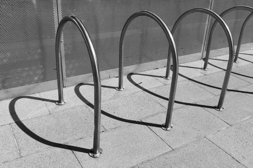 Free Minimalist steel bicycle rack casting shadows on pavement in city. Stock Photo