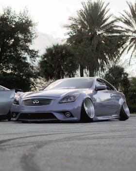 A sleek luxury sports car parked on a tropical street under palm trees.