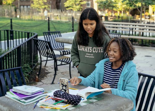 Little schoolgirls doing homework with smartphone