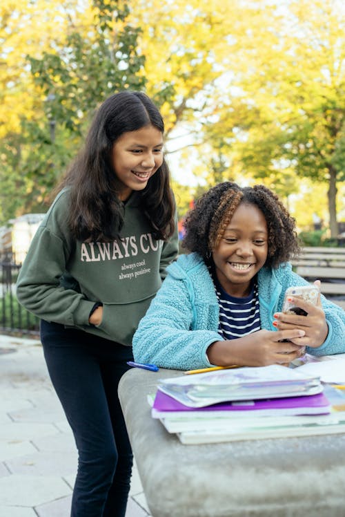 Free Multiracial little girls browsing smartphone together Stock Photo
