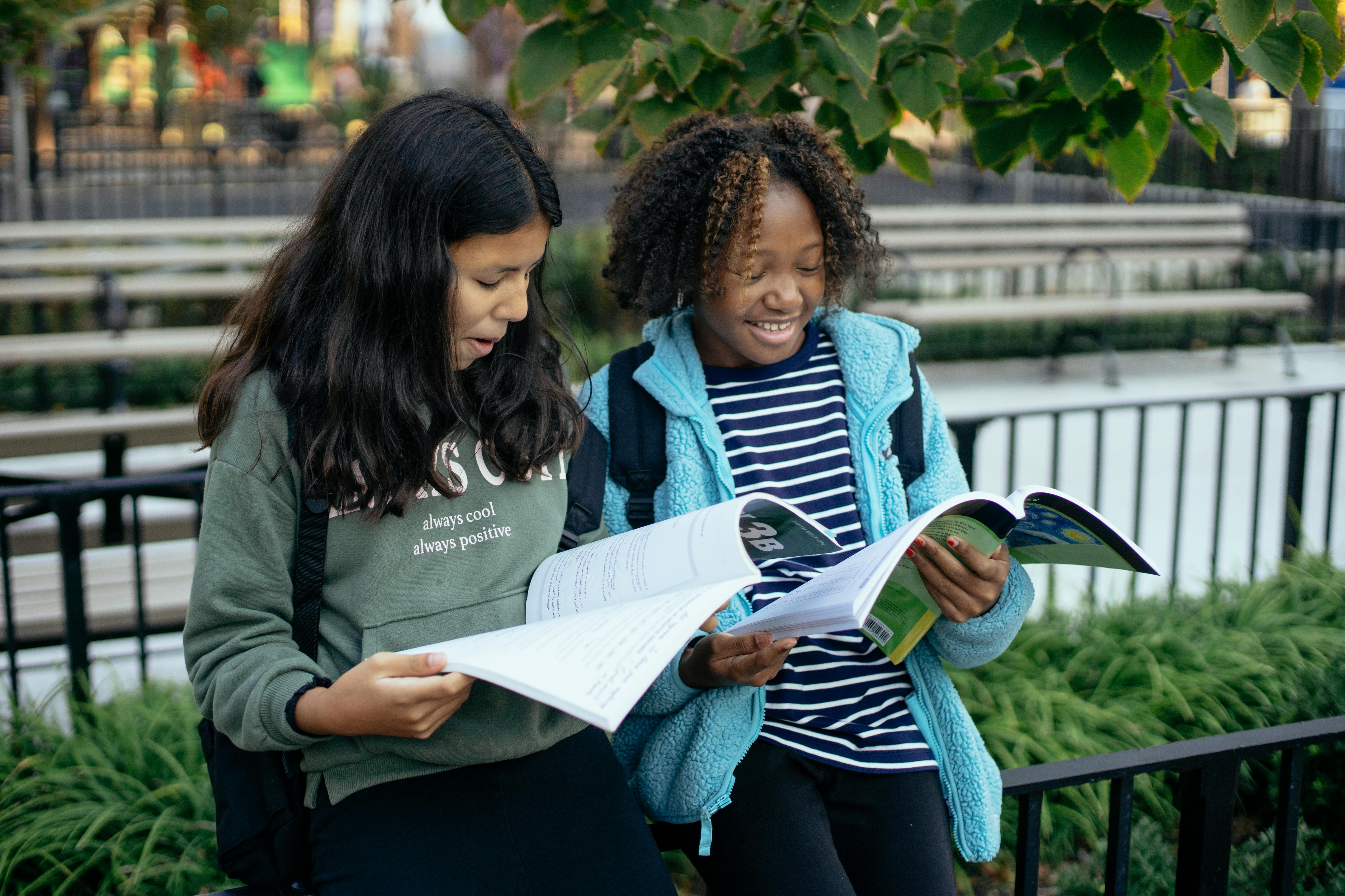 happy multiethnic girls studying together in park