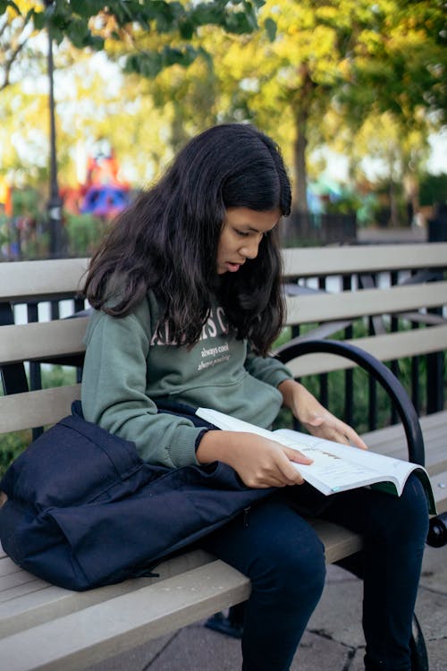 Hispanic child with book on bench