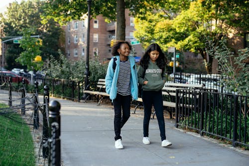 Smiling diverse girlfriends walking in park