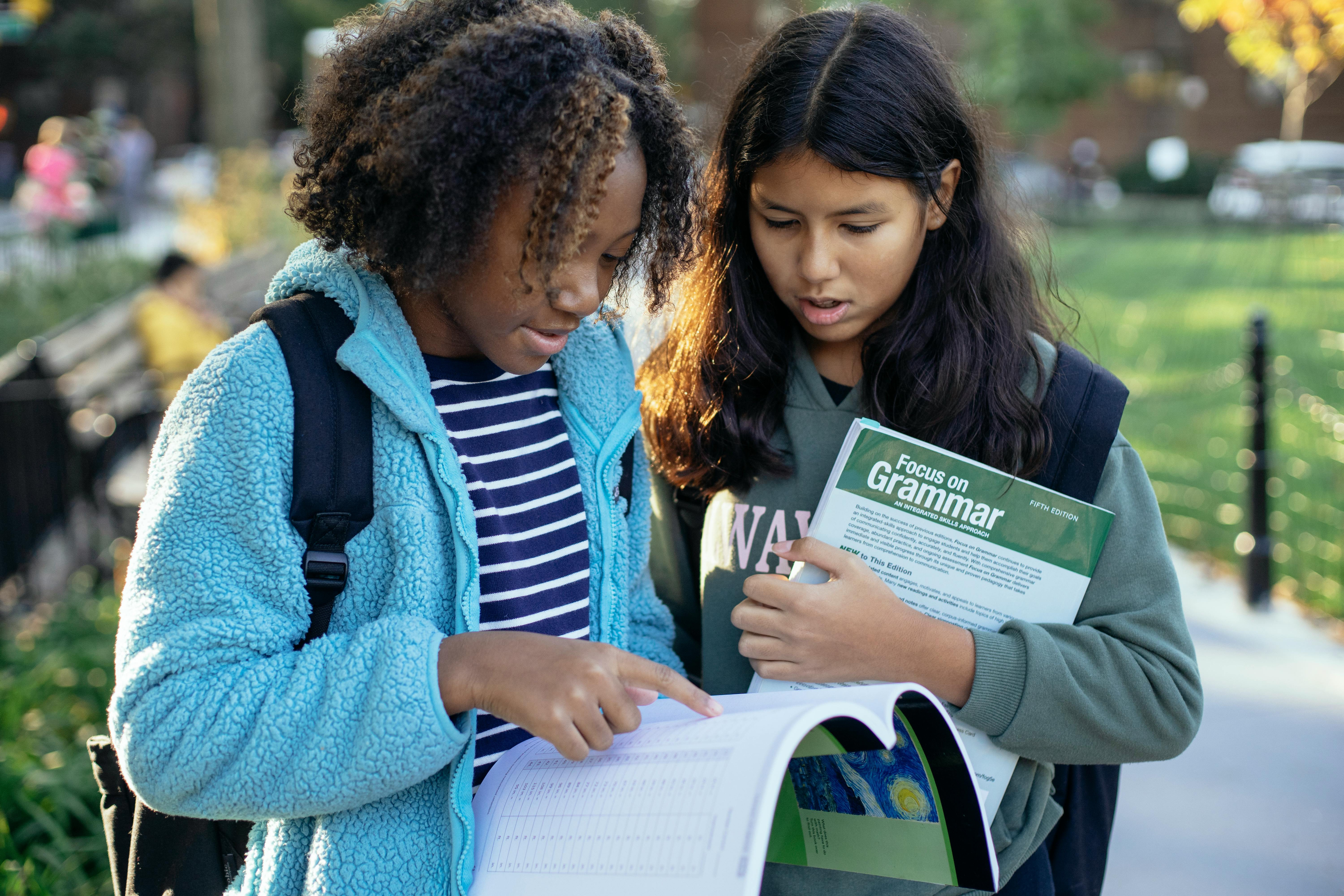 young schoolgirls with textbooks in park