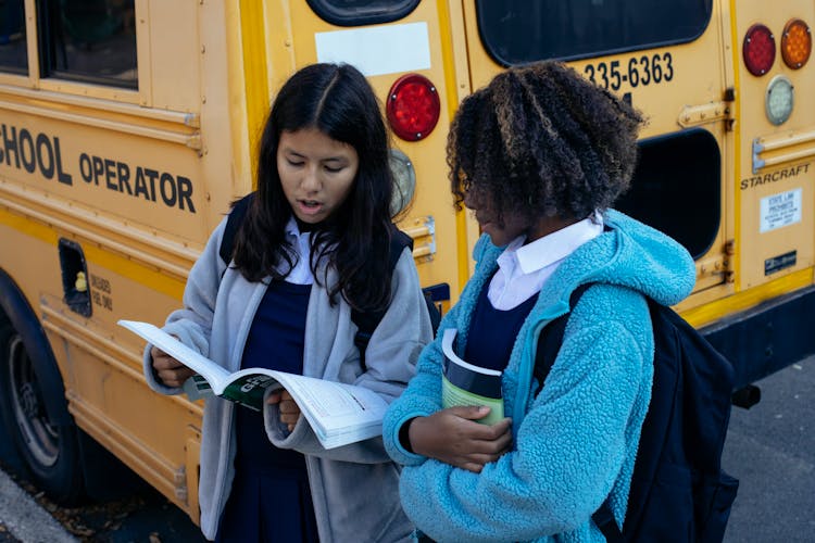 Multiracial Little Girls Near School Bus