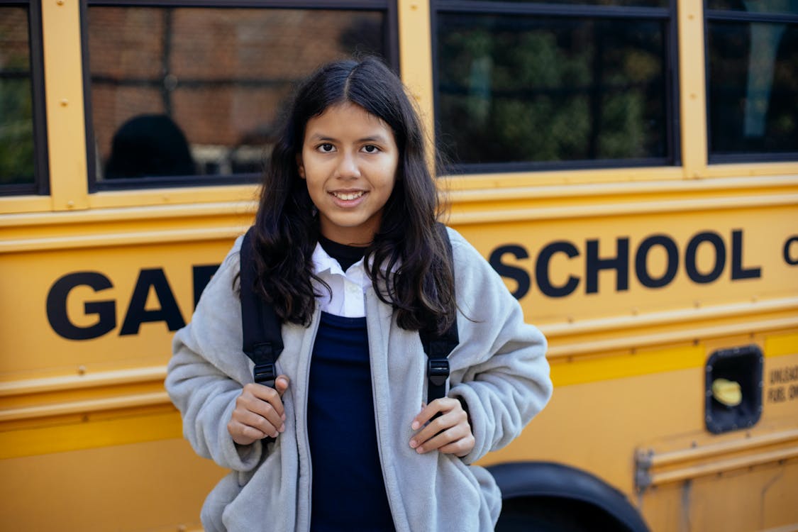Free Happy Hispanic girl near school bus Stock Photo
