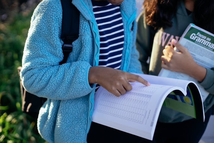 Crop Ethnic Schoolchildren Sharing Workbook On Shiny Street