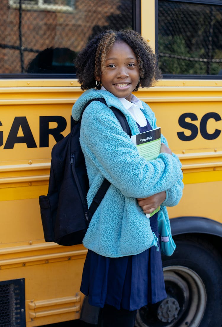 Glad African American Schoolgirl With Workbook On City Street