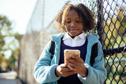 Content black girl using smartphone in autumn park