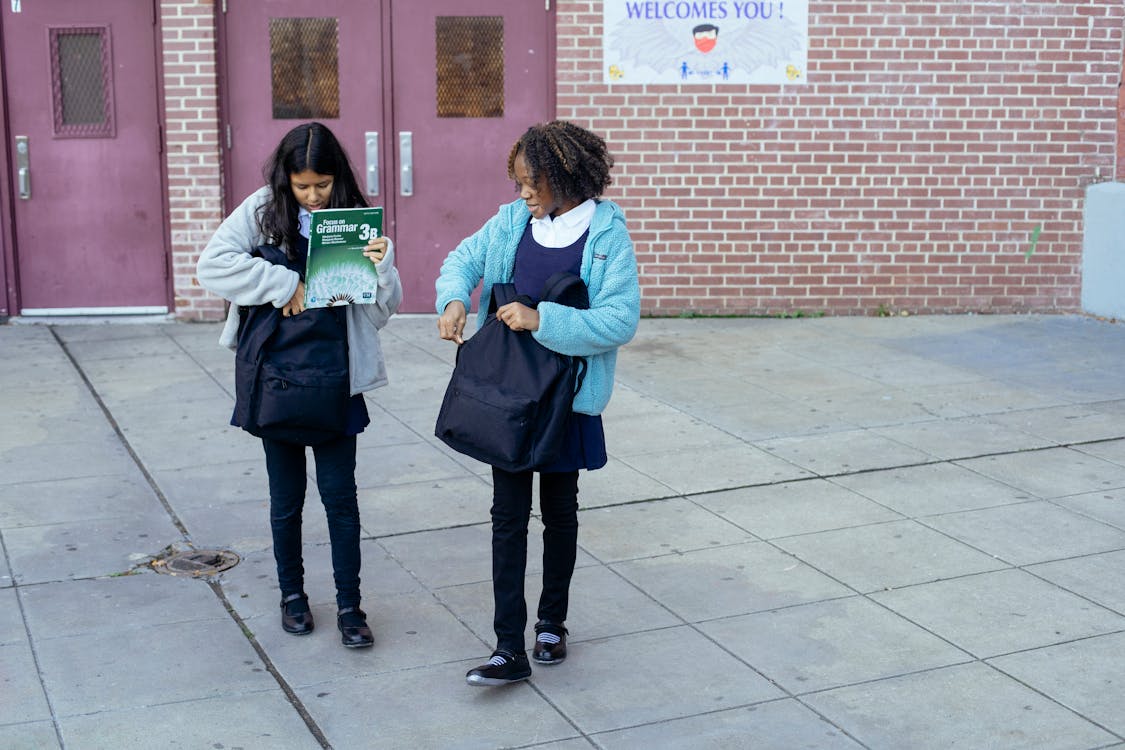 Schoolgirls carrying backpacks and leaving school together · Free Stock ...