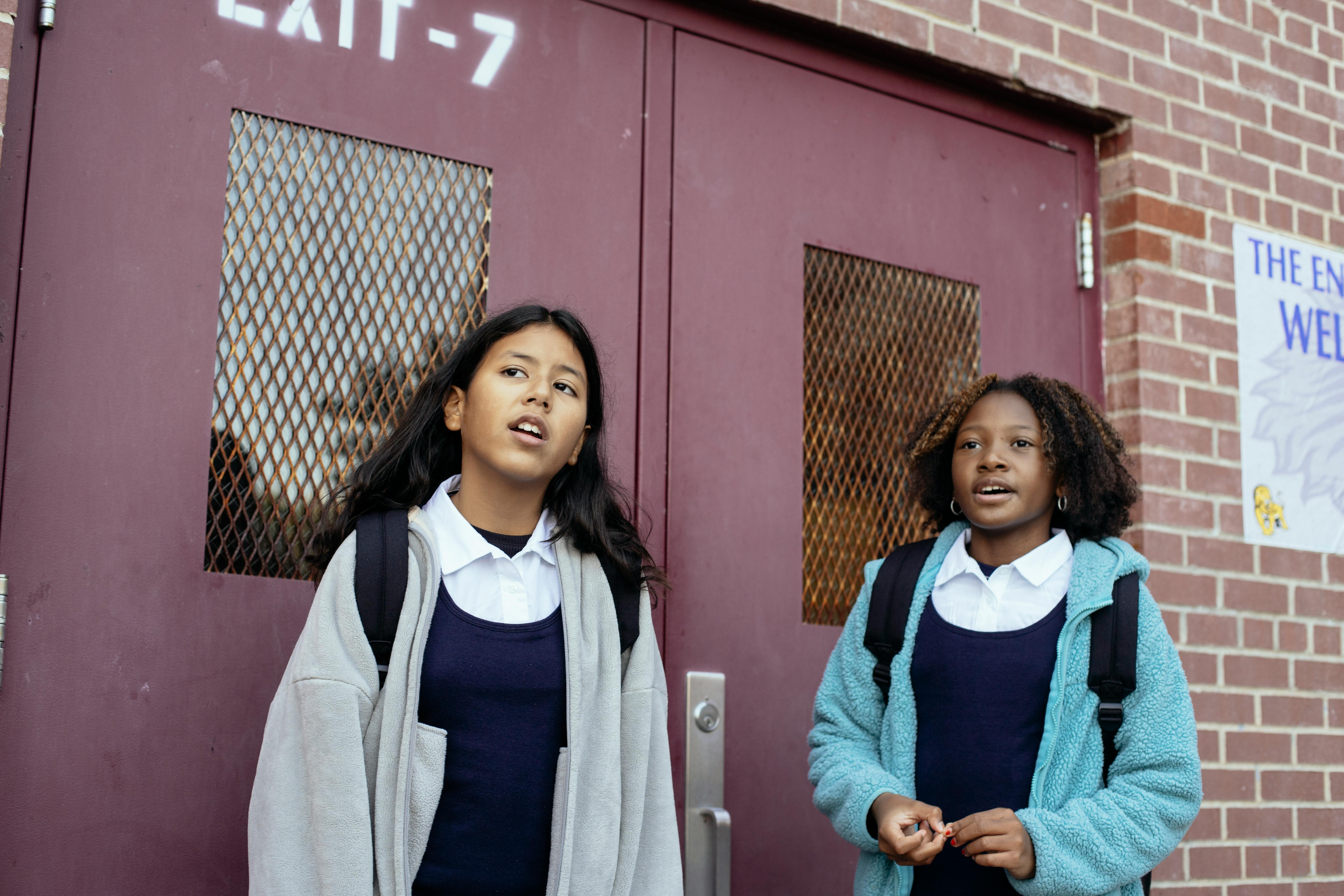 diverse schoolgirls standing near school door
