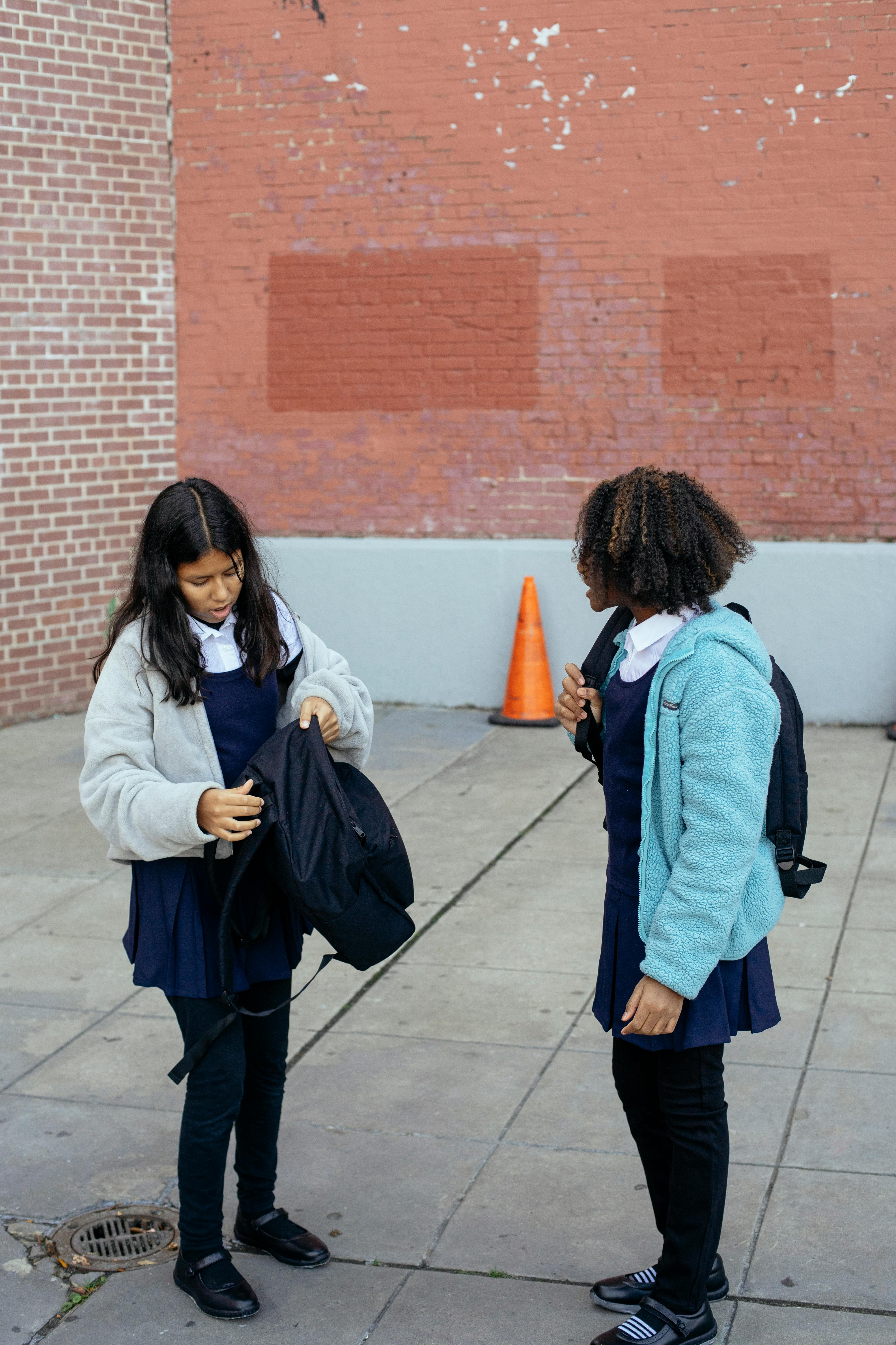 diverse schoolgirls standing with backpacks near school building