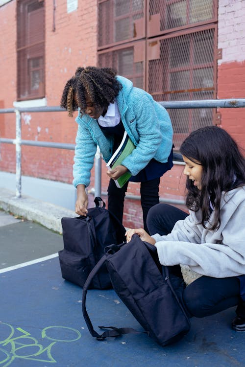 Free Cheerful adorable multiethnic schoolgirls preparing textbooks for learning Stock Photo