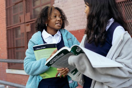 Two schoolgirls discussing lessons outdoors, holding educational books.