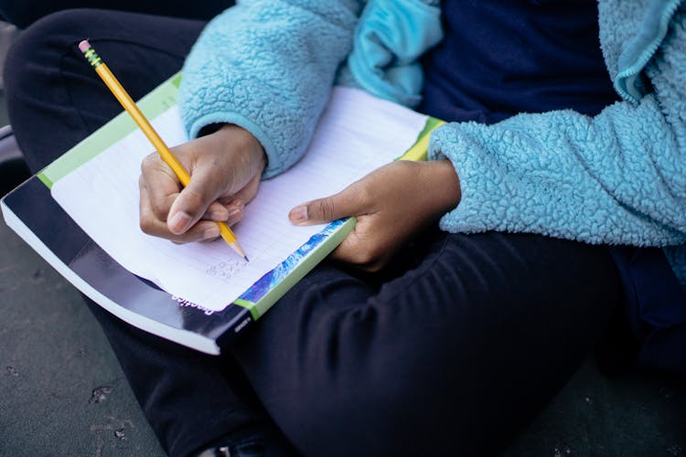 Clever Diligent Ethnic Child Doing Homework On Sheet Of Paper