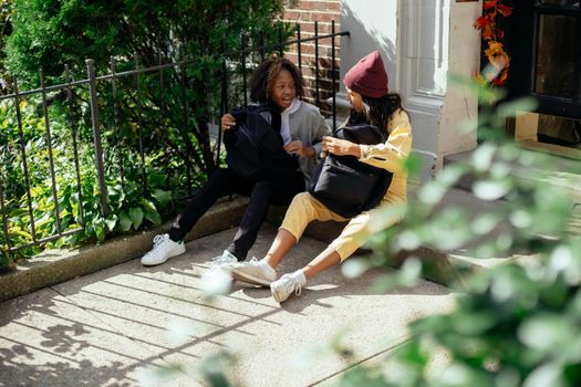几个可爱的不同种族的小女孩坐在家门口附近，互相看着、说着话