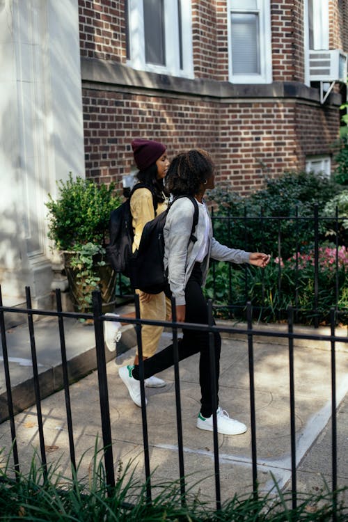 Free Multiracial girls walking on stairs near brick building Stock Photo