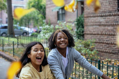 Cheerful diverse girls with smiling and laughing while throwing leaves