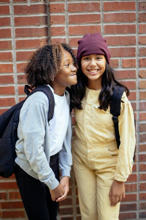Free Diverse children in casual clothes with backpacks standing together after school and smiling Stock Photo