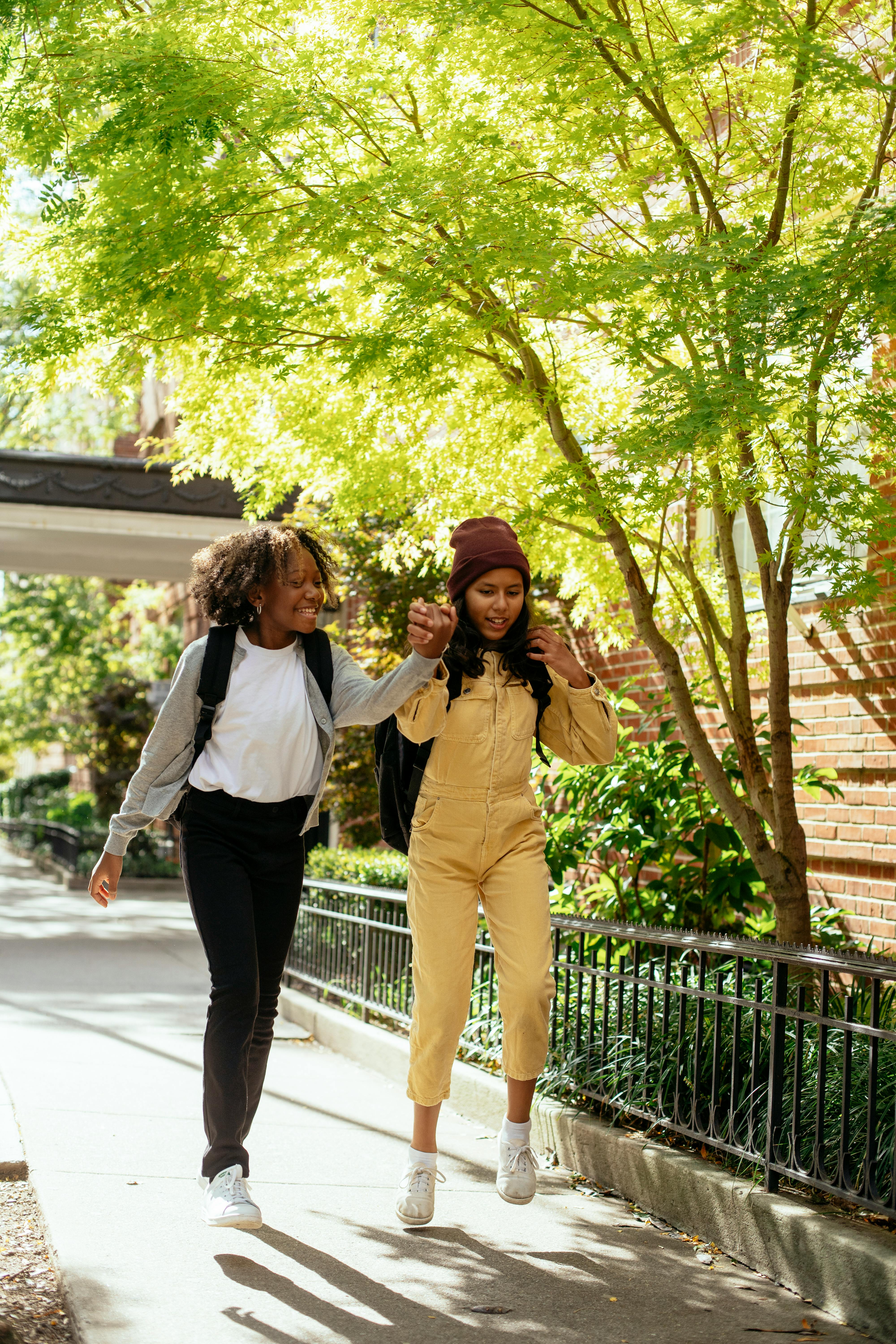 content multiethnic schoolchildren talking while walking on urban pavement