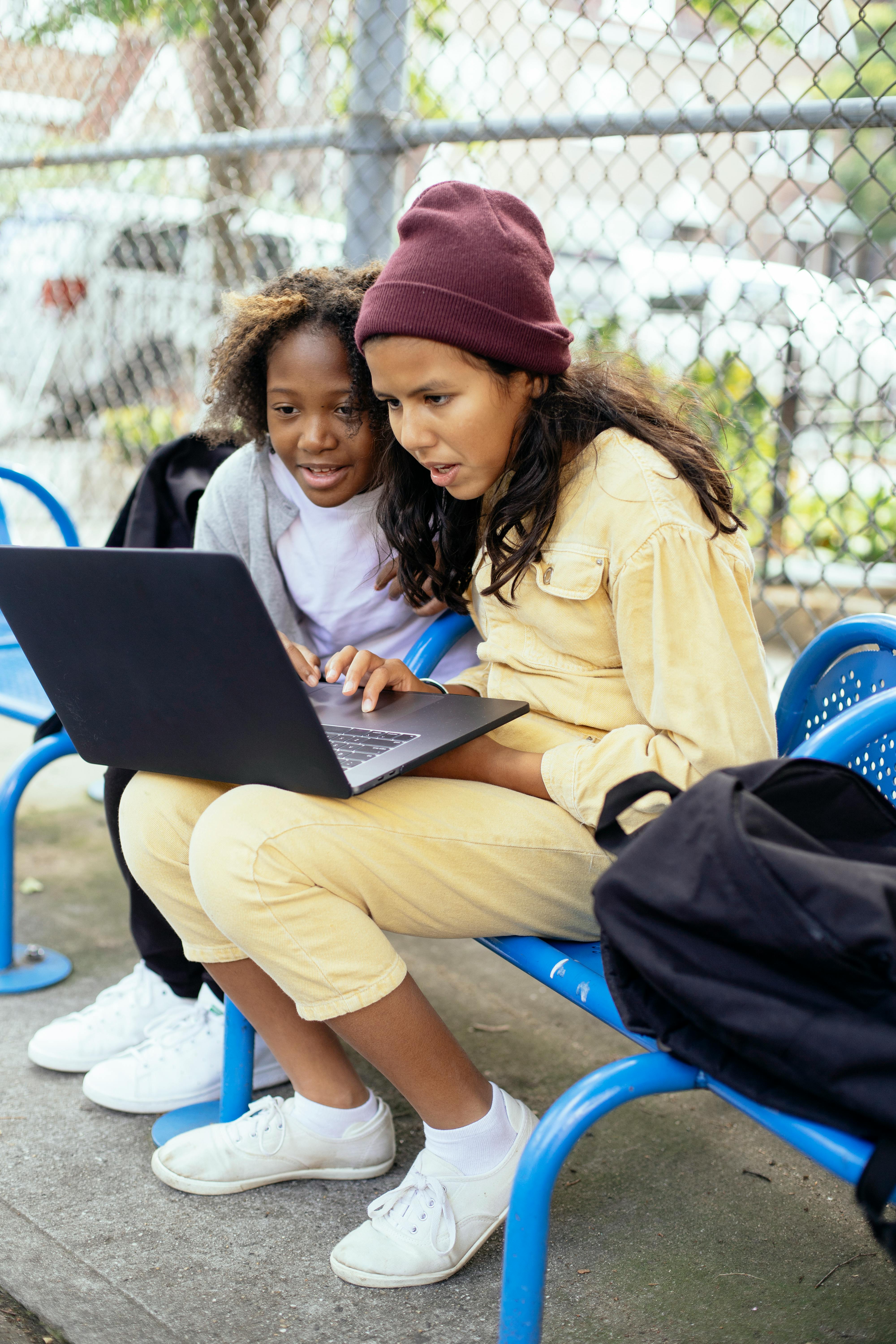 interested diverse schoolkids surfing internet on laptop in town