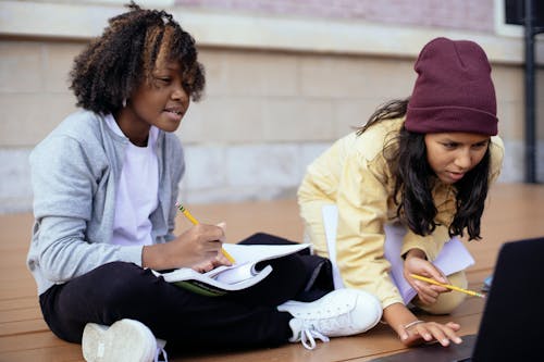 Attentive multiracial schoolchildren surfing internet on laptop while doing homework