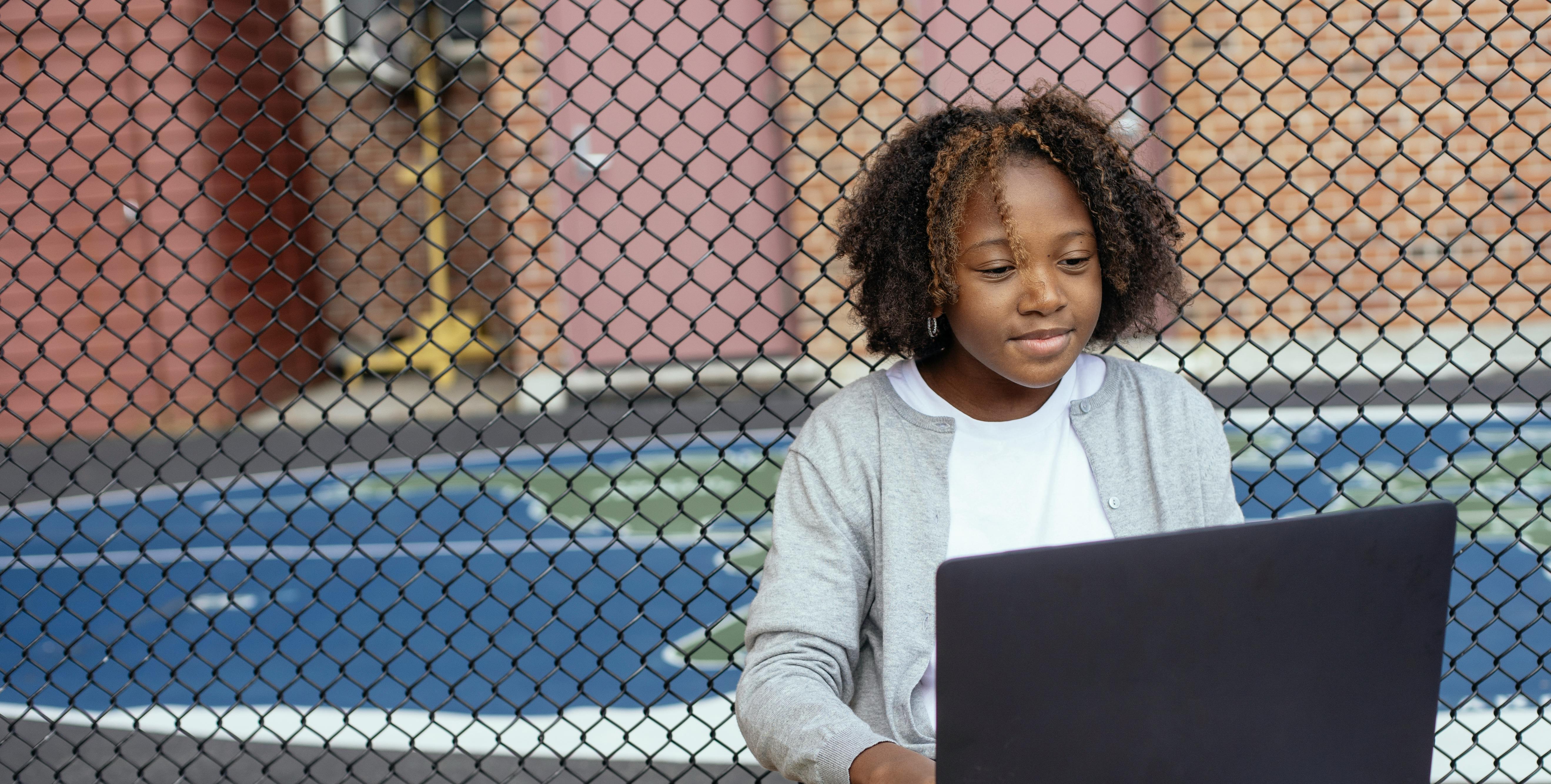 smiling black girl watching laptop on street