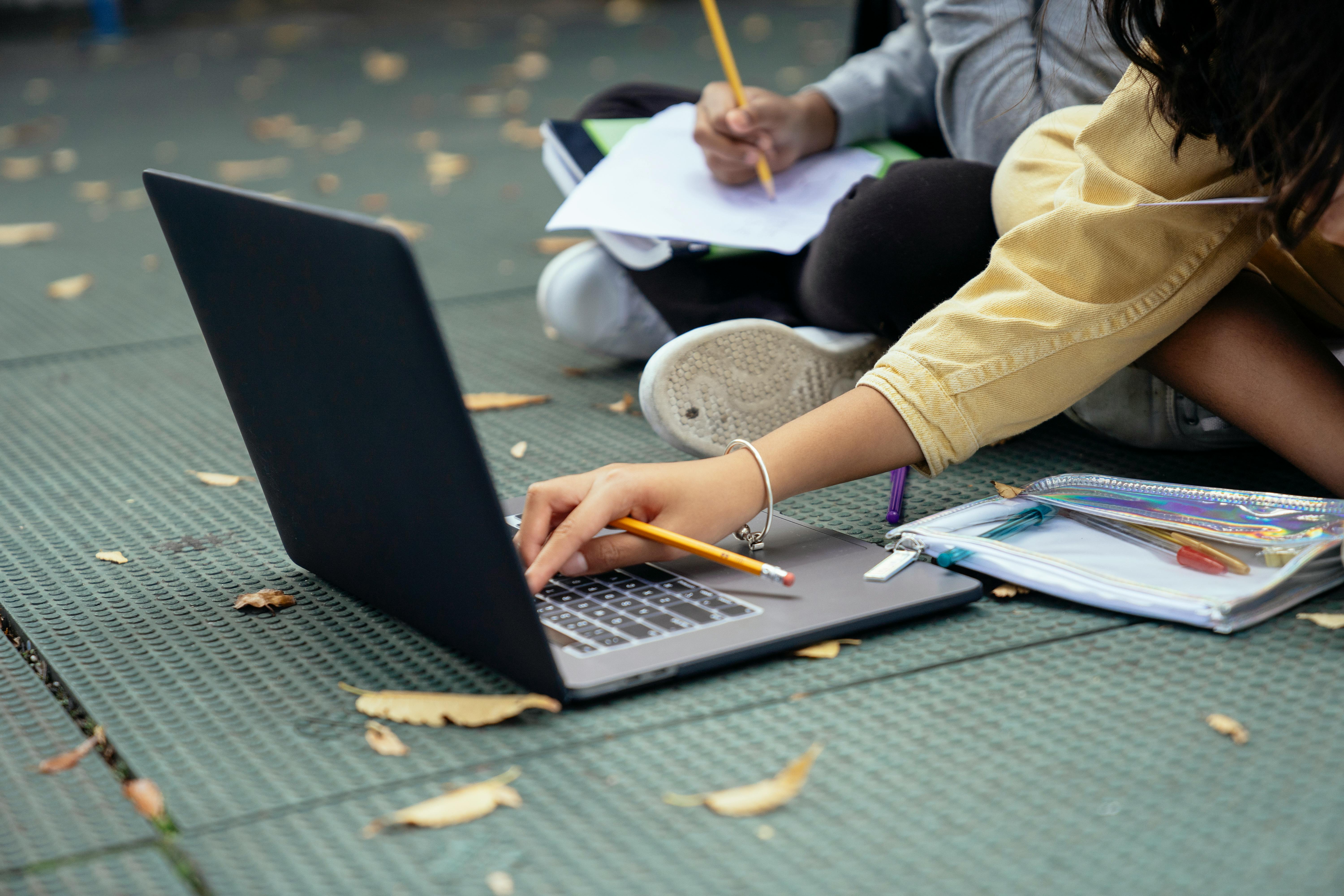 Faceless diverse schoolchildren typing on laptop while studying on ...