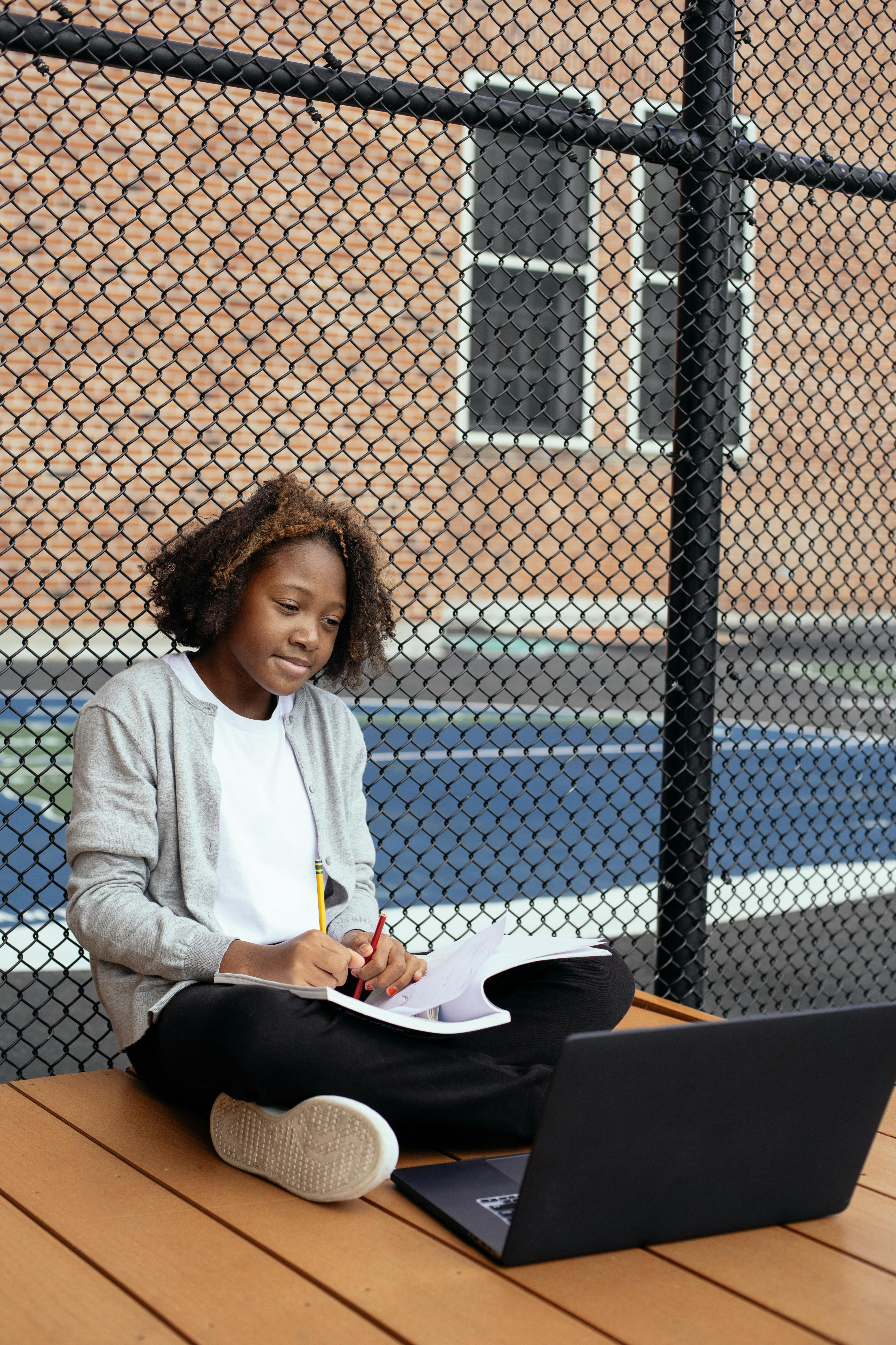 black girl doing homework on sports ground