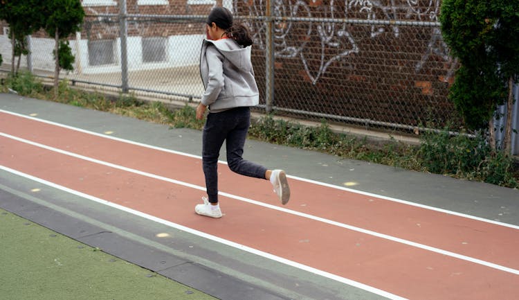 Faceless Girl Jogging On Sports Ground